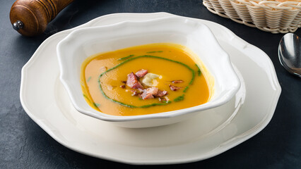 Fresh pumpkin cream soup with bacon pieces.