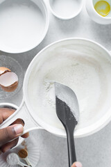 All purpose flour in a white sieve, sifting baking flour into a large bowl