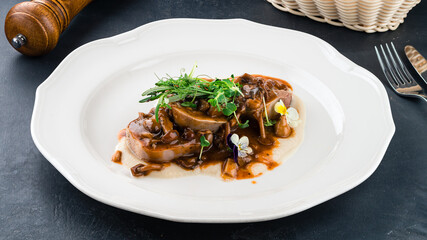 Fried beef tongue medallions with sauce and microgreens.