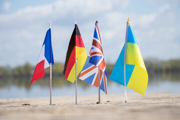 Flags of Germany and France and Great Britain and Ukraine on the sand in Ukraine on the shore, flags of countries and friendship