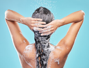 Rinsing it out. Shot of an unrecognizable woman washing her hair in the shower against a blue background. - obrazy, fototapety, plakaty