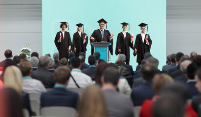Professor and graduate students standing on a podium in front of people