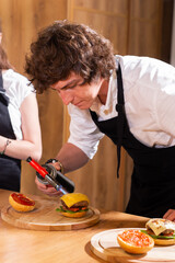 Preparing delicious burgers. Chef cooking meat burgers with beef, cheese and vegetables. Close-up