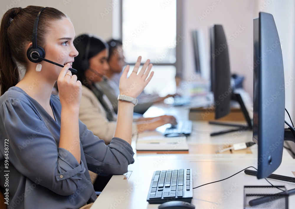 Poster Providing the best solution and direction. Shot of a young call centre agent working in an office with her colleagues in the background.