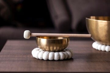 A portrait of a tibetan singing bowl or himalayan bowl, with a mallet lying on top of it to make a...