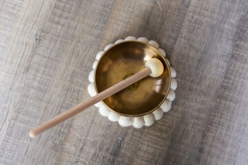 A portrait of a tibetan singing bowl, also called a himalayan bowl, with a mallet standing in it to...