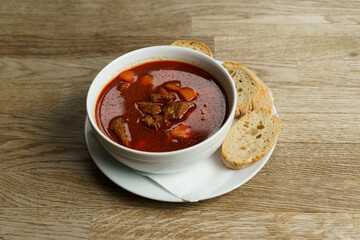 Traditional Hungarian Goulash Soup with Bread on a wooden table