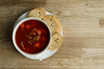 Traditional Hungarian Goulash Soup with Bread on a wooden table