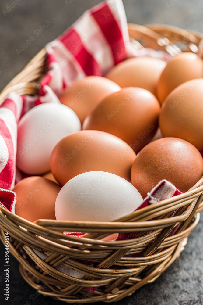 Sticker Whole chicken eggs in basket on black table.