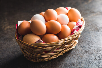 Whole chicken eggs in basket on black table.