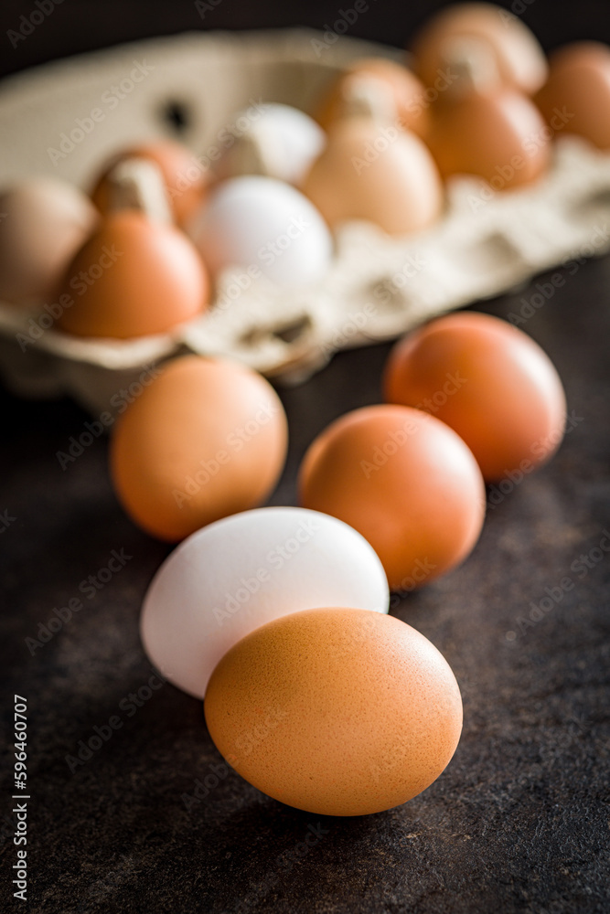 Poster whole chicken eggs on black table.