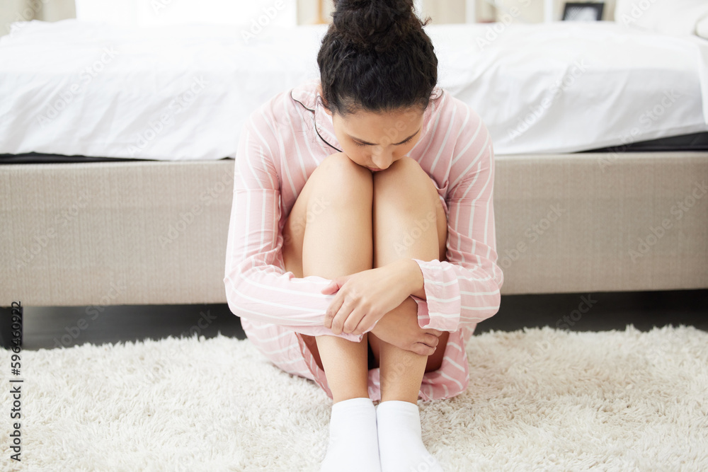 Poster My heart is broken. Shot of a young woman looking depressed while sitting in her room.