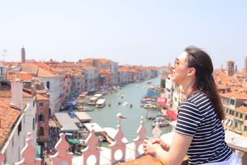 Fototapeta na wymiar Mujer joven con camiseta de rayas marineras en azotea con vistas al Gran Canal de Venecia