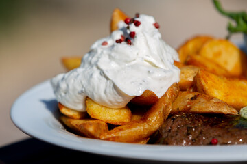 Mouthwatering steak with potato edges and sour creme with tempting, culinary flavors
