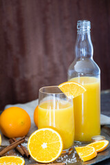 set with freshly squeezed orange juice with bottle, glass with drinking straw and some slices of freshly cut oranges