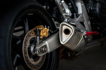 Detail of the exhaust and brake on the wheel of a sports motorcycle.