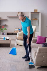 Old male contractor cleaning the house