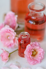Composition with pure natural organic rose essential oil in glass bottle, luxury perfumery ingredient for premium fragrance, skin care products, anti-age beauty treatment. Fresh flowers