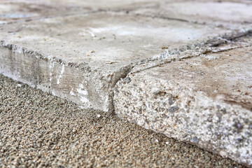 Large old concrete tile blocks on layer of sand - pavement construction, closeup detail