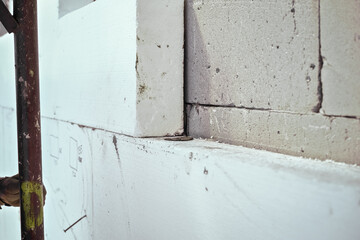 White polystyrene foam board blocks for heat insulation on bare concrete wall at construction site, closeup detail