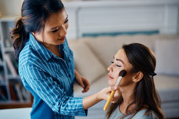 Young woman getting her makeup done by Asian beautician.