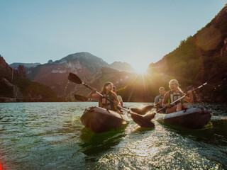 A group of friends enjoying fun and kayaking exploring the calm river, surrounding forest and large natural river canyons during an idyllic sunset. © .shock