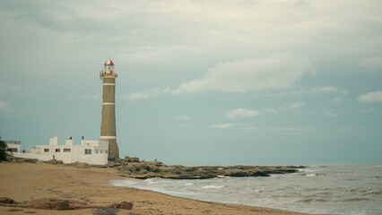 portrait of san ignacio lighthouse, uruguay a cloudy afternoon in front of the rough sea with waves
