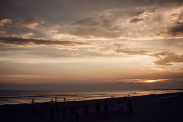 Sunset in summer vacation on the beach, with clouds in the sky. View from the seashore near the sand
