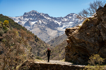 Woman hiking in Vereda de la Estrella. Peaks of Sierra Nevada National Park in the background (Alcazaba, Mulhacén)