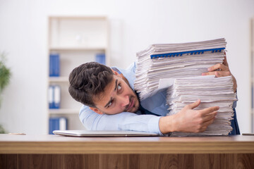 Young male employee and too much work in the office