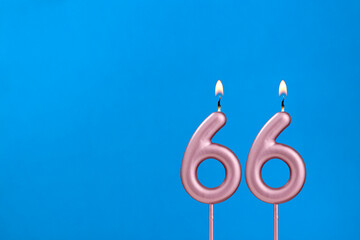 Number 66 - Burning anniversary candle on blue foamy background