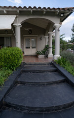 View of the steps leading to the colonial style house facade and entrance. 