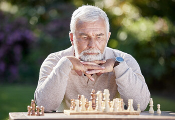 A little bit of luck, a little bit of logic. Shot of a senior man playing a game of chess outside.