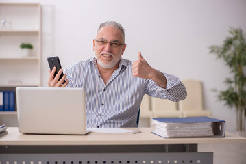 Old male employee working at workplace