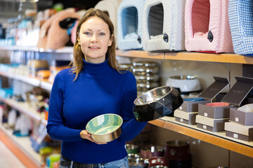 Cheerful woman buying bowl for pets in pet store