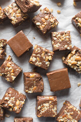 Top view of chocolate fudge with nuts on a marble board, chocolate fudge cut into pieces, fudge candy on a chopping board