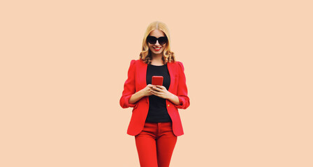 Portrait of beautiful smiling elegant lady woman with smartphone wearing red business blazer on white background