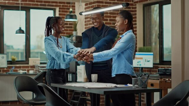 Happy people uniting hands in meeting and celebrating business success, feeling cheerful about achievement. Team of colleagues being happy with company results for development in boardroom.