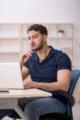 Young male employee sitting at workplace