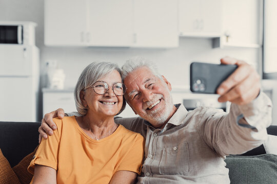 Happy old couple taking selfie on cellphone, smiling senior mature spouses middle aged wife and retired husband laughing holding phone make self portrait on smartphone camera, focus on mobile display.