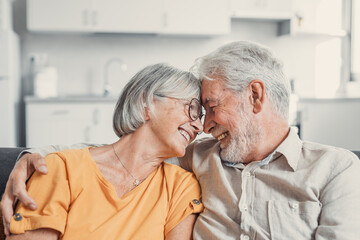 Happy laughing older married couple talking, laughing, standing in home interior together, hugging with love, enjoying close relationships, trust, support, care, feeling joy, tenderness.