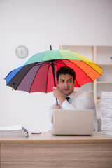 Young male employee holding an umbrella in the office