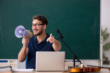 Young male music teacher holding megaphone in the classroom