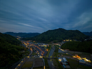 Aerial view of lights from small rural town between mountains at dusk