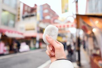 ショッピングストリートで和菓子を食べ歩きする女性の手元のアップ