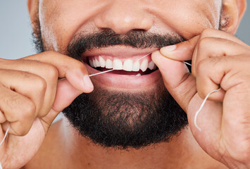 Giving his teeth a little extra care. Studio shot of an unrecognizable man using dental floss...