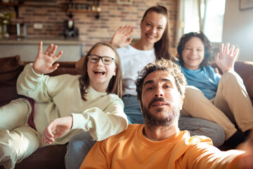 Fototapeta premium Young family having a video call on their phone in the living room of their home