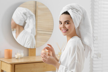 Beautiful happy woman in stylish bathrobe with cream in bathroom