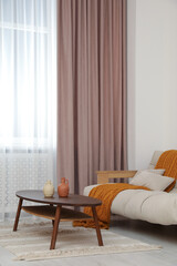 Living room with pastel window curtain, wooden table and sofa