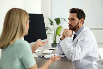 Doctor consulting patient at wooden table in clinic